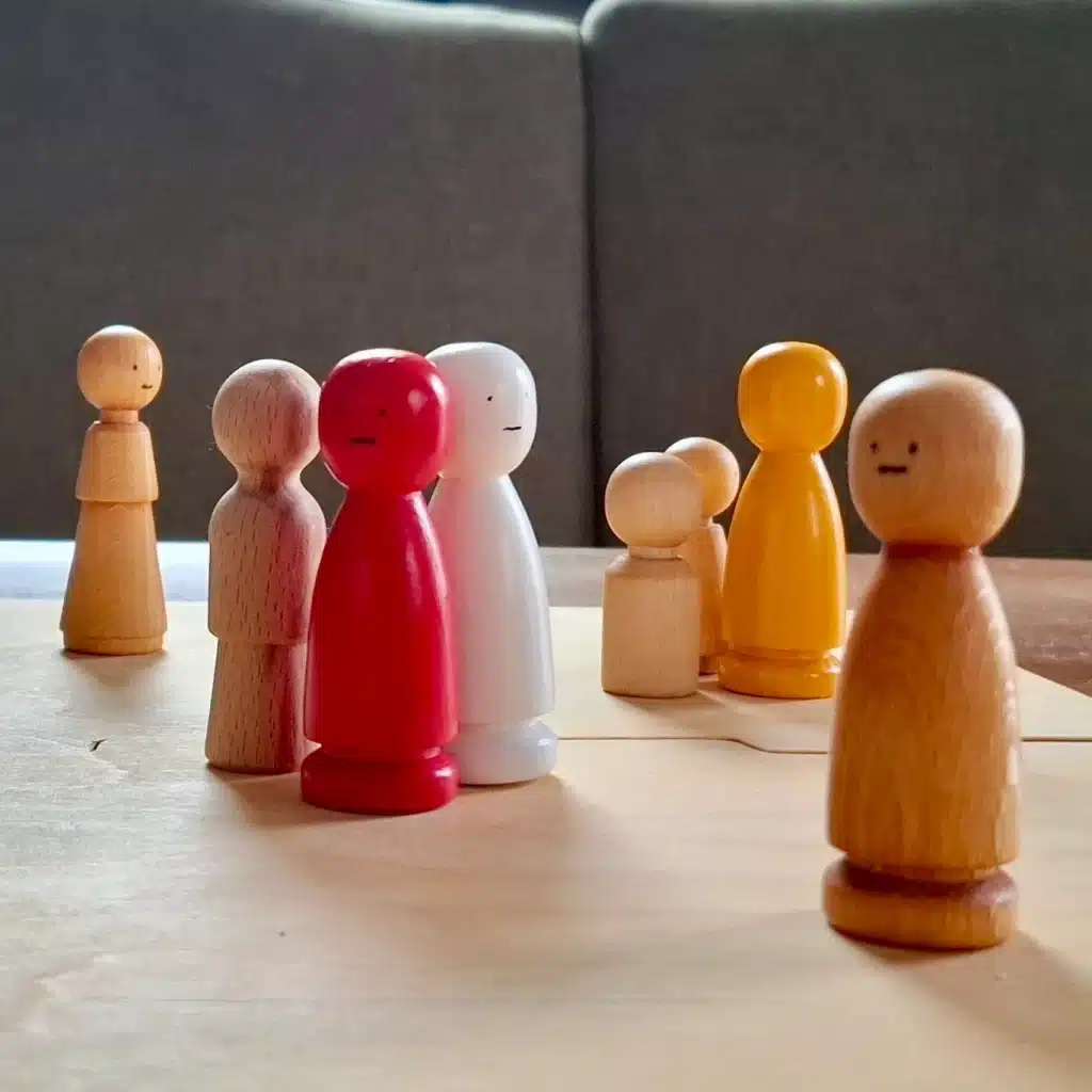 bunte Figuren stehen auf Systembrett, Methode in systemischer Beratung