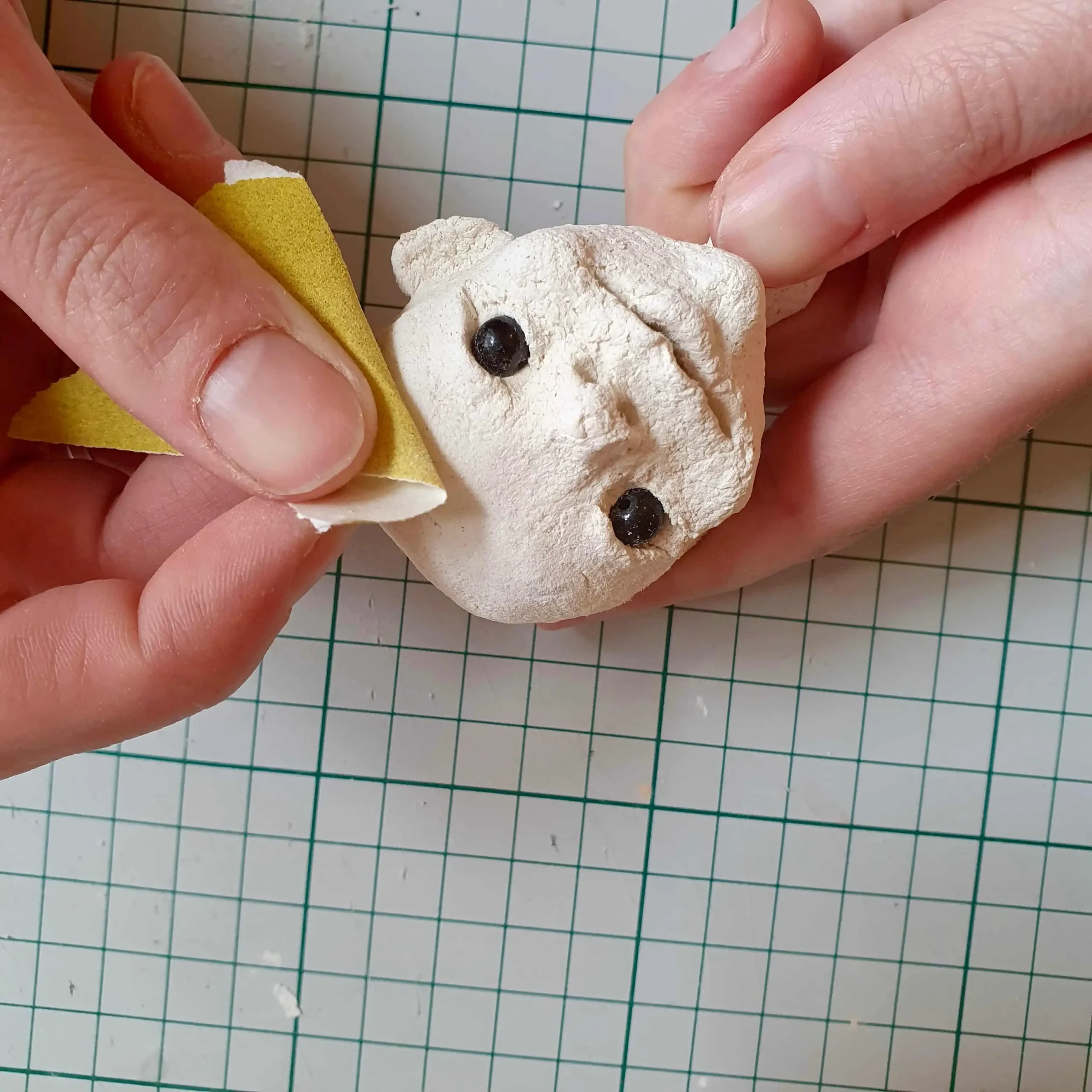 Puppenkopf wird geschliffen, liegt in der Hand, Figurenbau in Figurentherapie